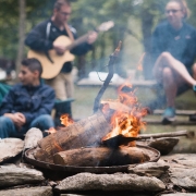 Picture of a people playing the guitar around a campfire.